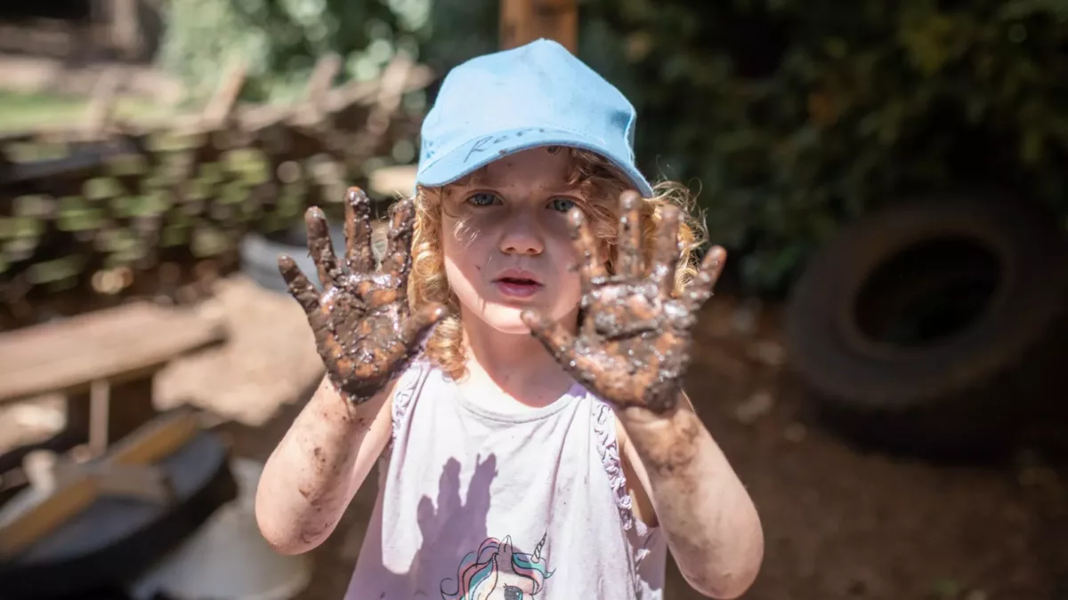 child with muddy hands, held up
