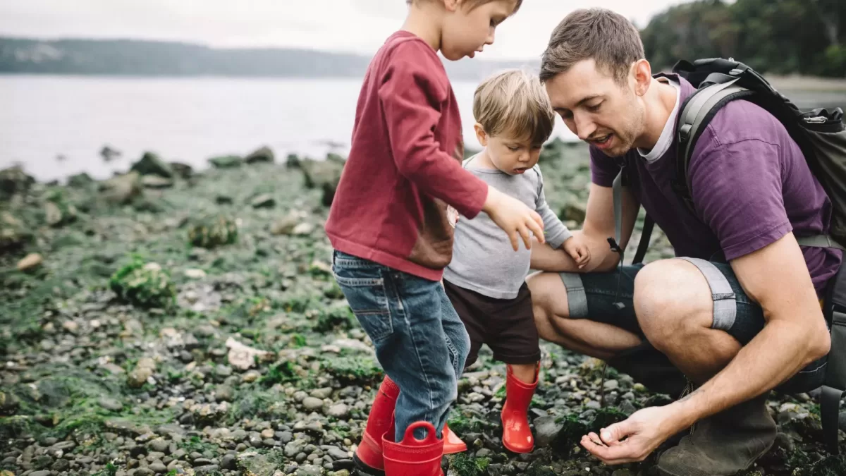 2 boys looking at pebbles with a teacher