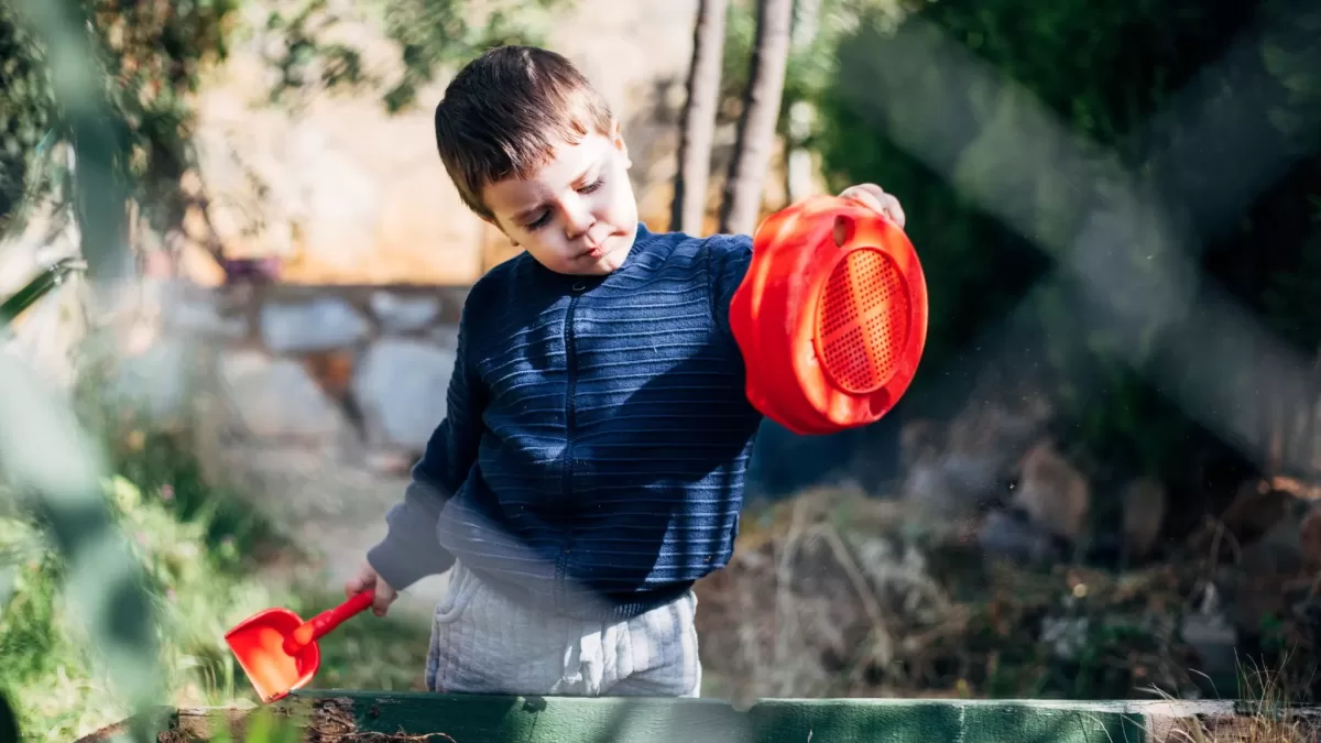 Boy holding a red bucket and spade
