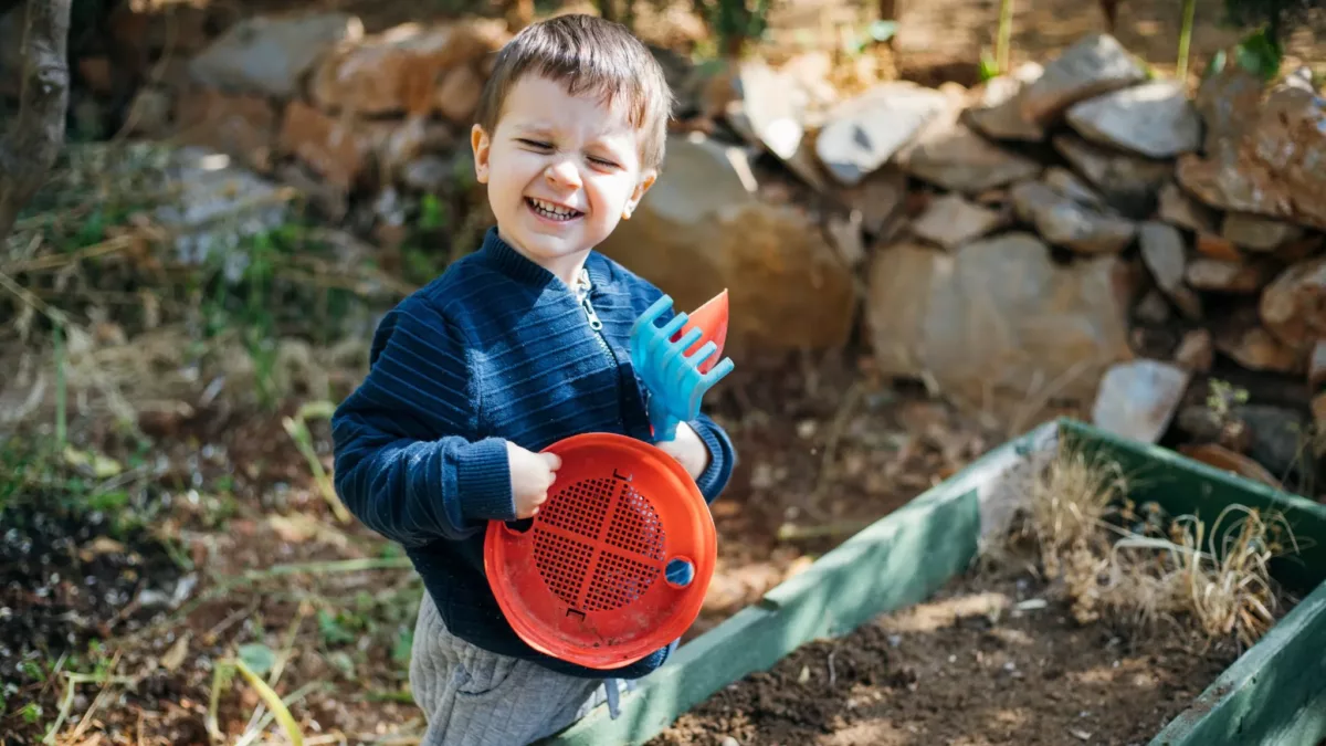 Boy with bucket and spade smiling